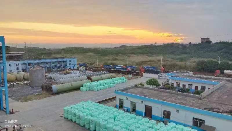 Vue aérienne de l'usine Guangxi Jinhua - Zone de stockage avec sacs verts CPE et bâtiments industriels